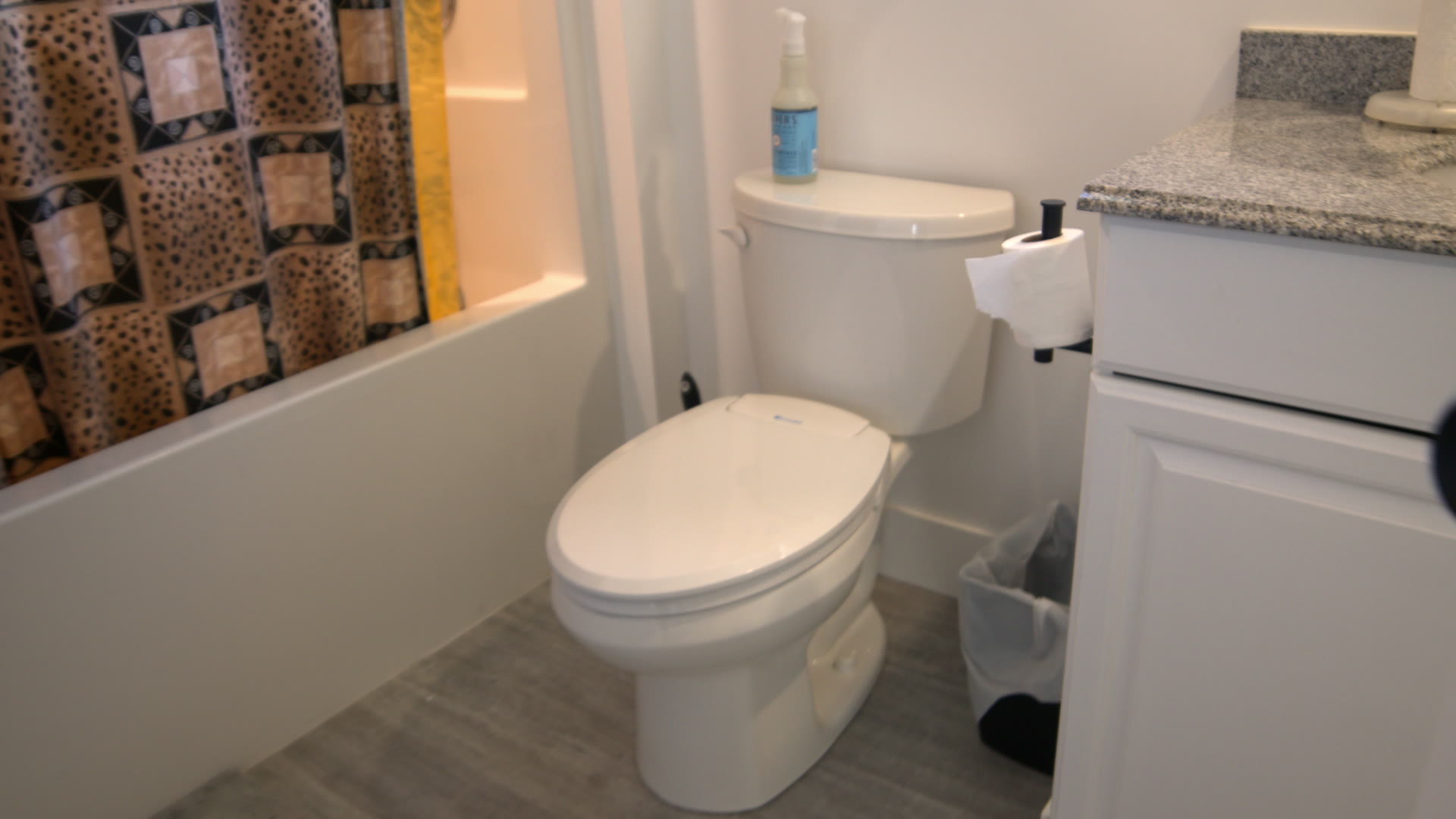 Bathroom: tub with leopard-print curtain, toilet and granite vanity